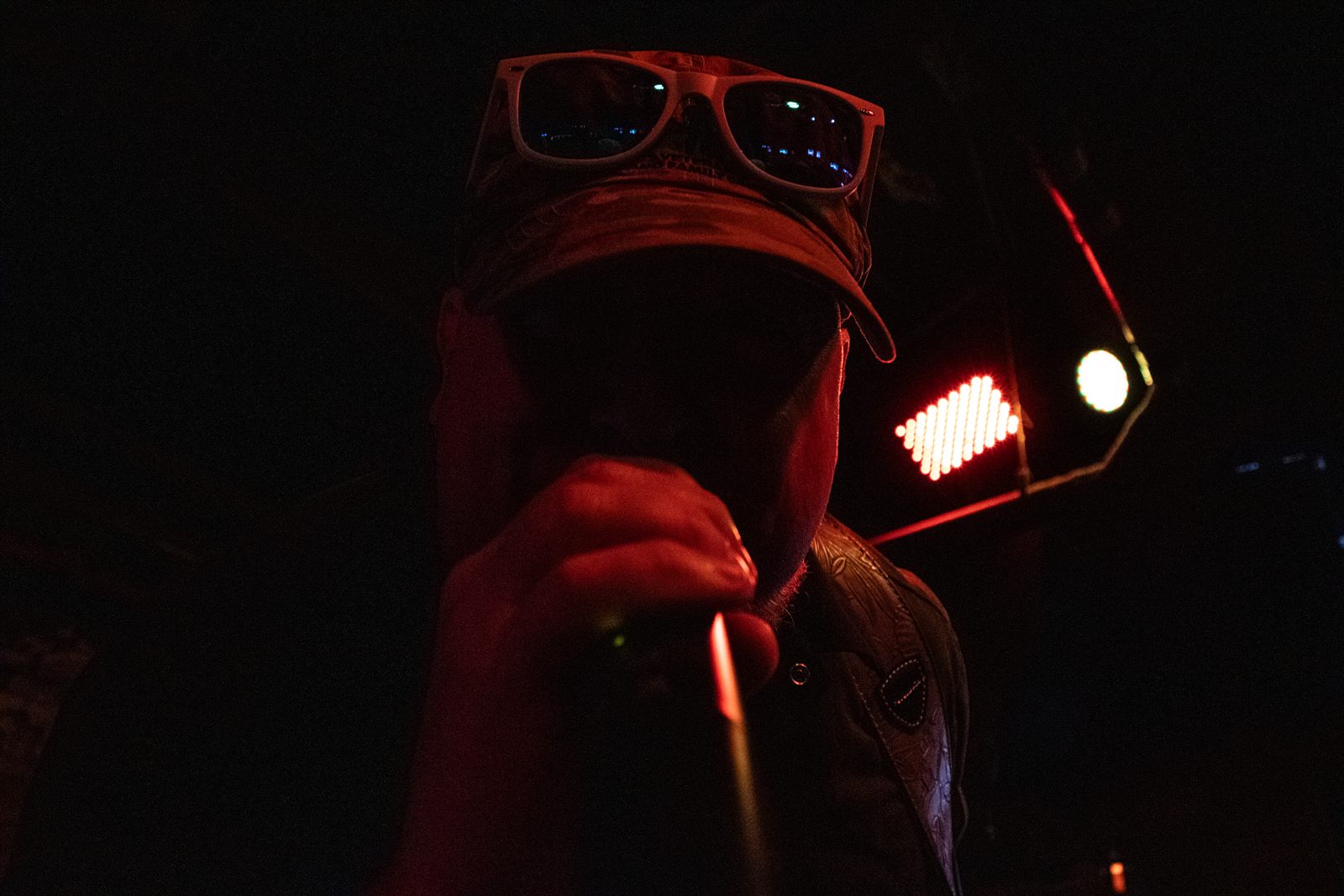Tenderheds — the singer at the microphone, face under a cap, a stage lamp behind him