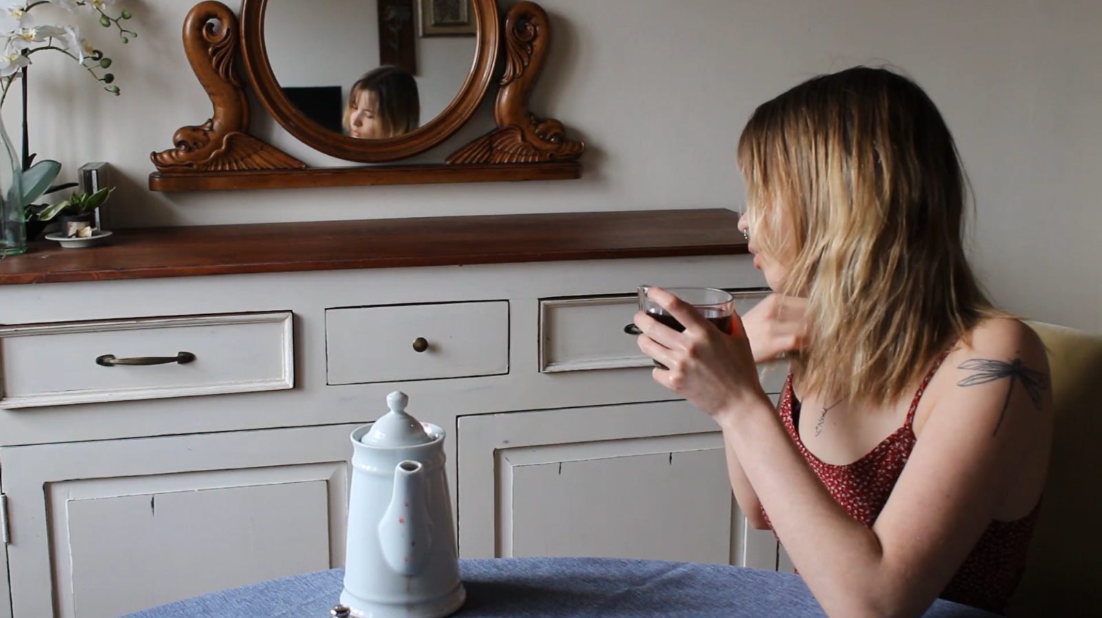 Pose — at the dresser, her reflection in the mirror behind her